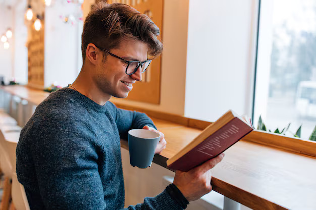 glad-young-man-resting-cafe-reading-interesting-book-drinking-tea_8353-6242